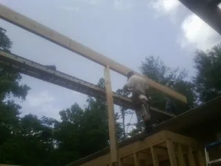 Carpenter setting a ridge beam over a new addition frame — Ice Dam Removal by Roofing Brothers in Holton