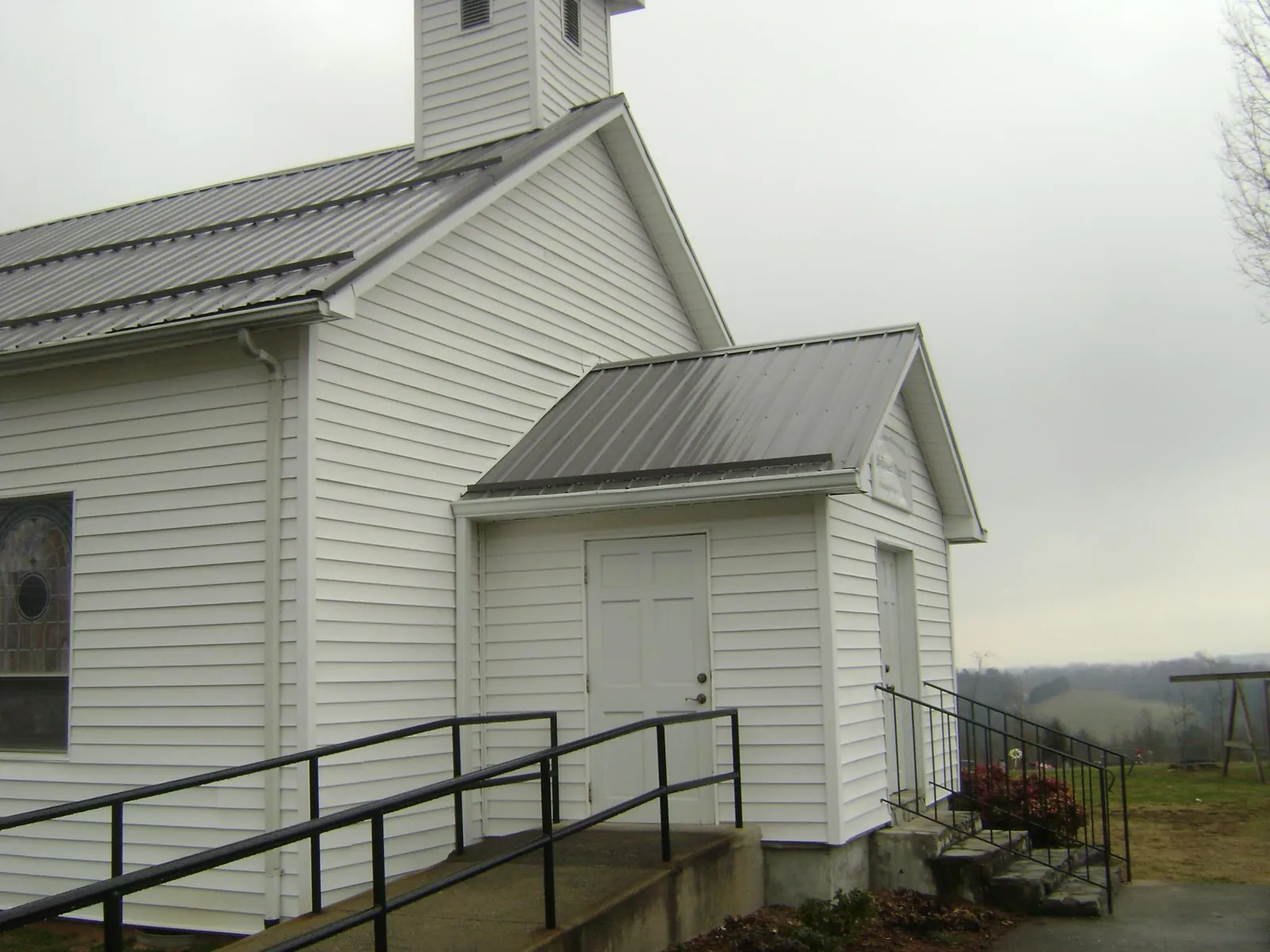 Gray metal roof on a white clapboard church with a steeple in Holton