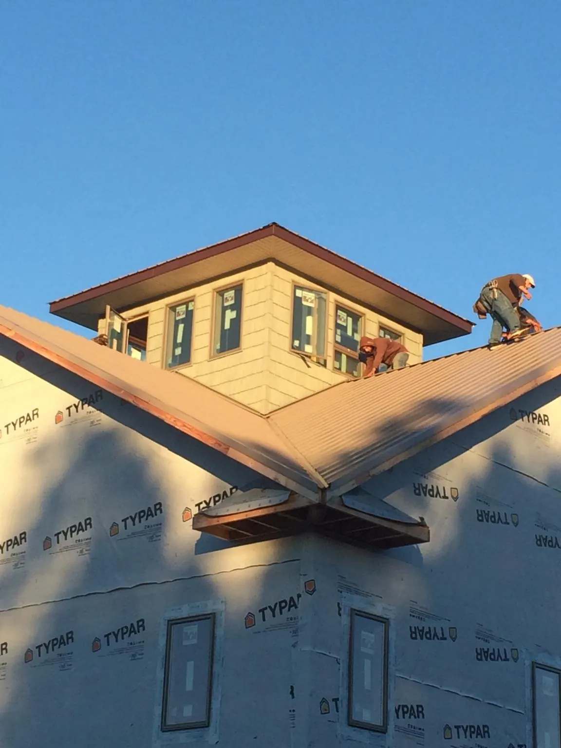Roofers working around a rooftop cupola on a new metal roof at sunset — Roof Waterproofing in Holton by Roofing Brothers